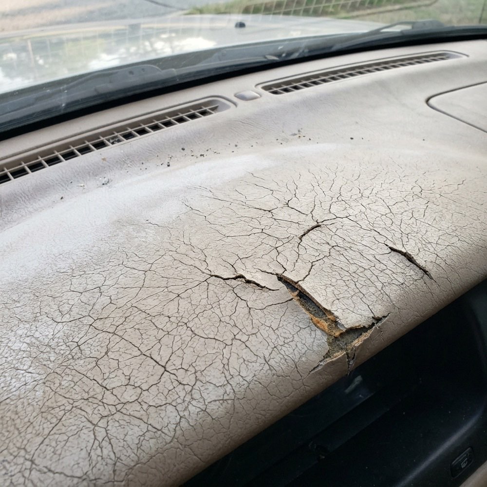 A beige dashboard top dried out and cracked by the sun