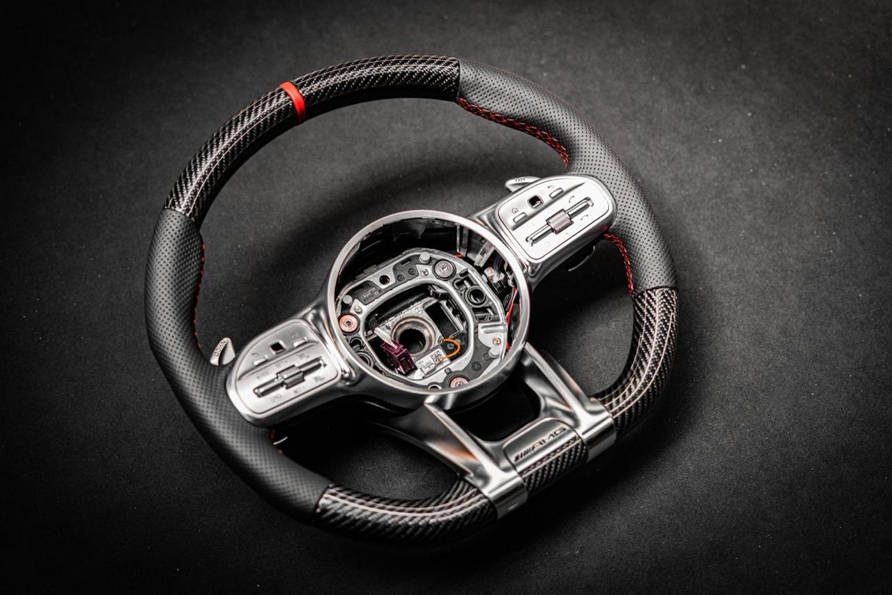 A carbon steering wheel with black leather grips and a red zero mark