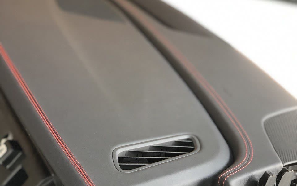 A dashboard re-trimmed in black leather with red stitching