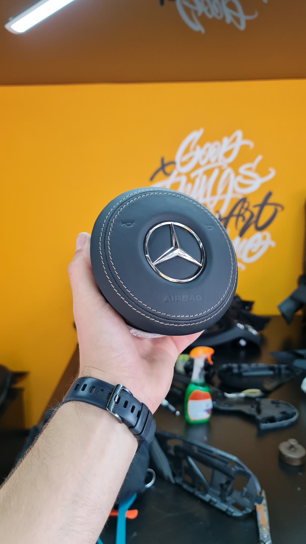 A Mercedes airbag cover wrapped in black leather with tan stitching