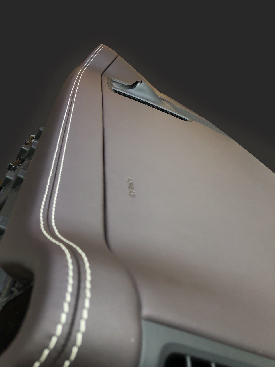 A dashboard in brown leather with white double stitching