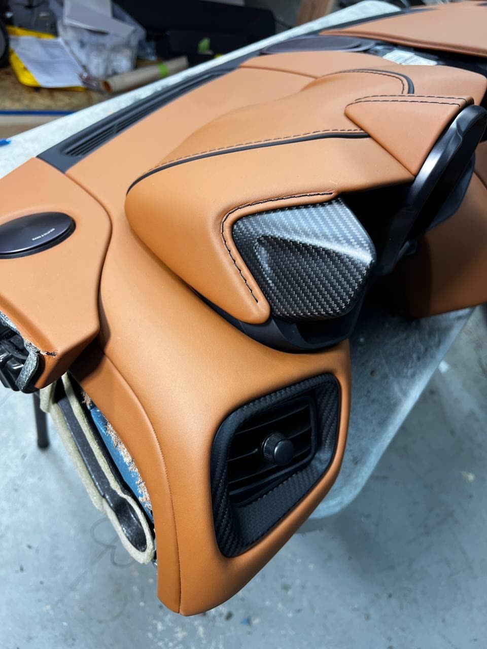 A dashboard in cognac leather with black stitching and carbon trim
