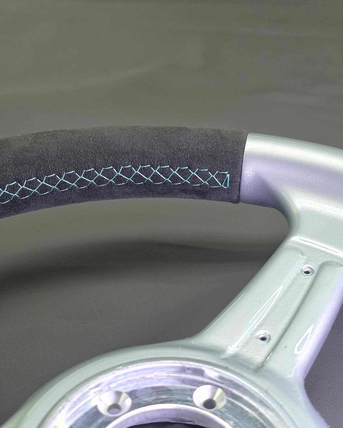 A pale blue cross stitch on black Alcantara.