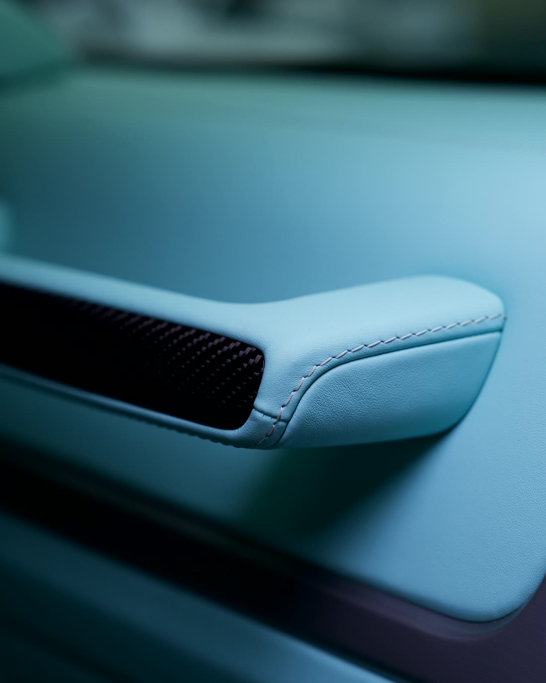 A topstitch that follows the armrest curve into the carbon trim.