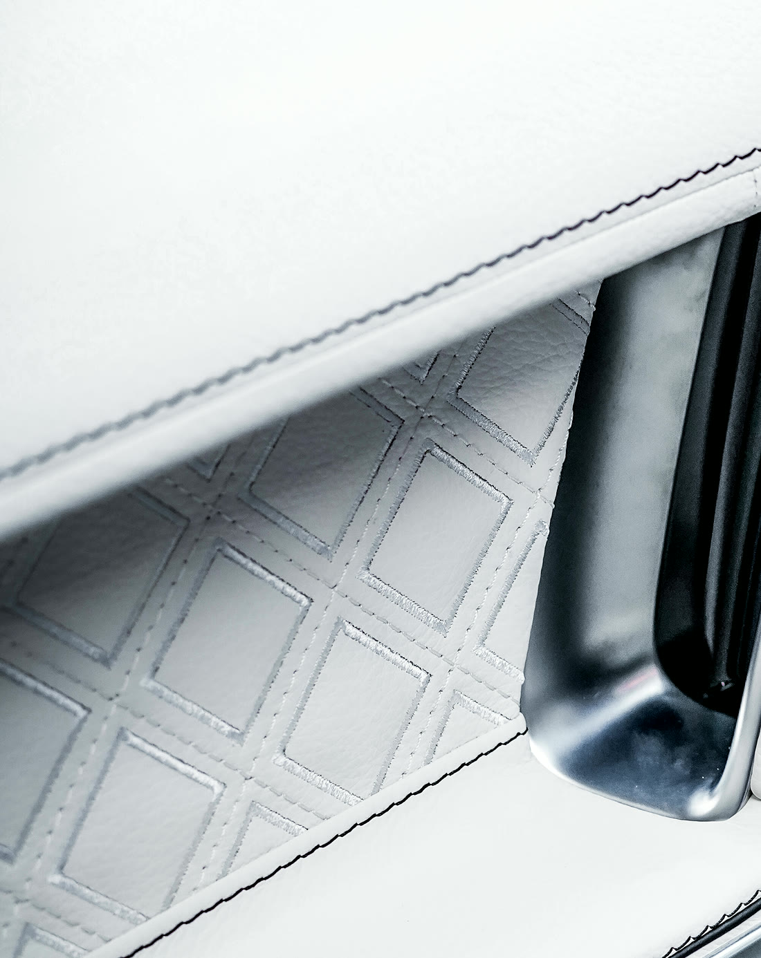A quilted white door insert with a dark double stitch around it.