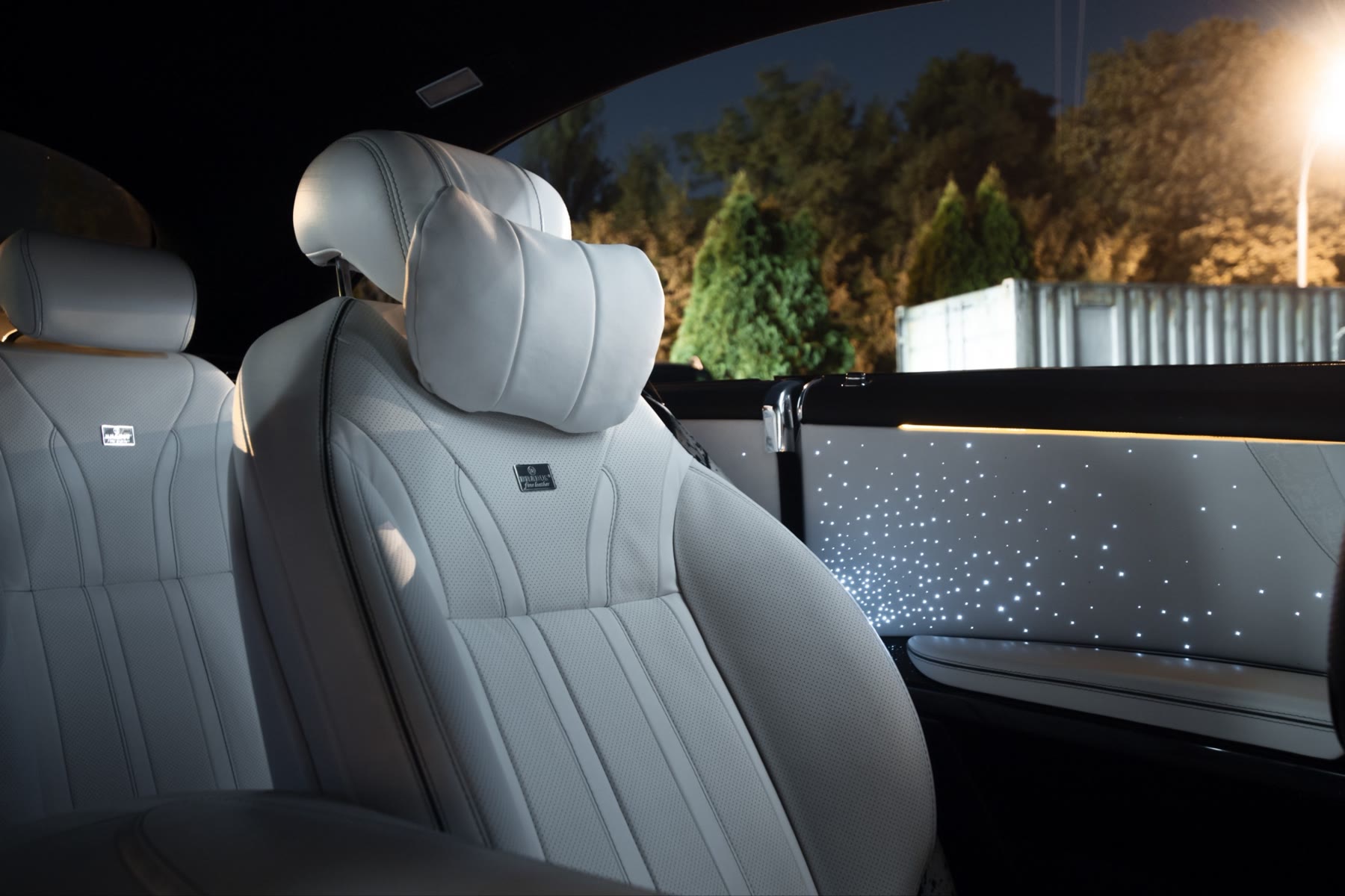 A rear seat in white leather next to a door panel with a starlight insert