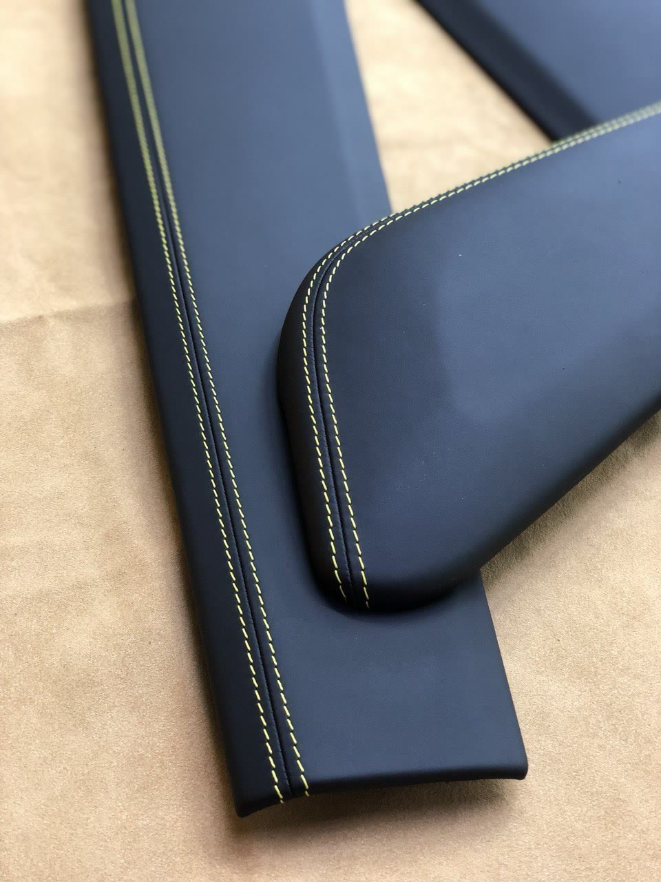 A navy leather armrest with a yellow contrast double stitch