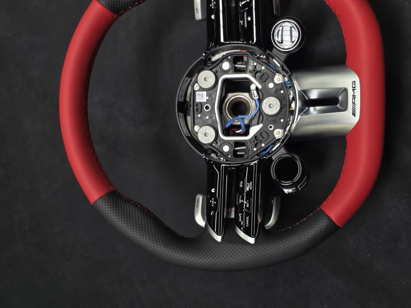 A steering wheel with red leather at the top and bottom and black grips