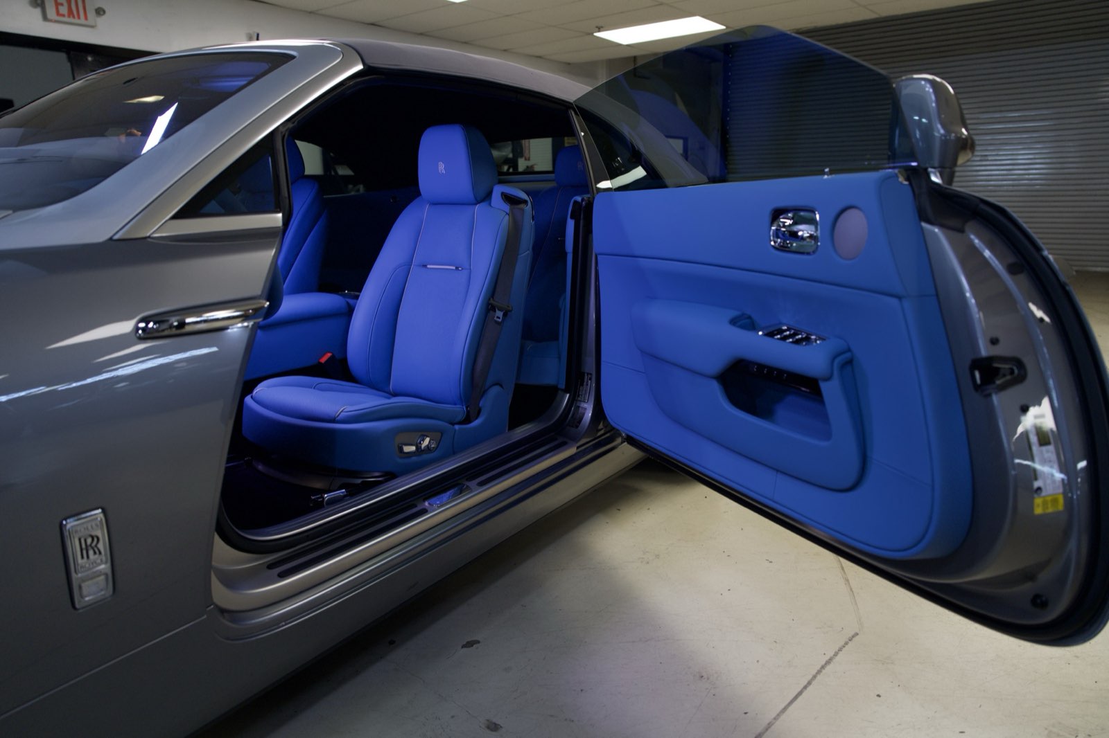 A grey Rolls-Royce with the door open on a royal blue cabin