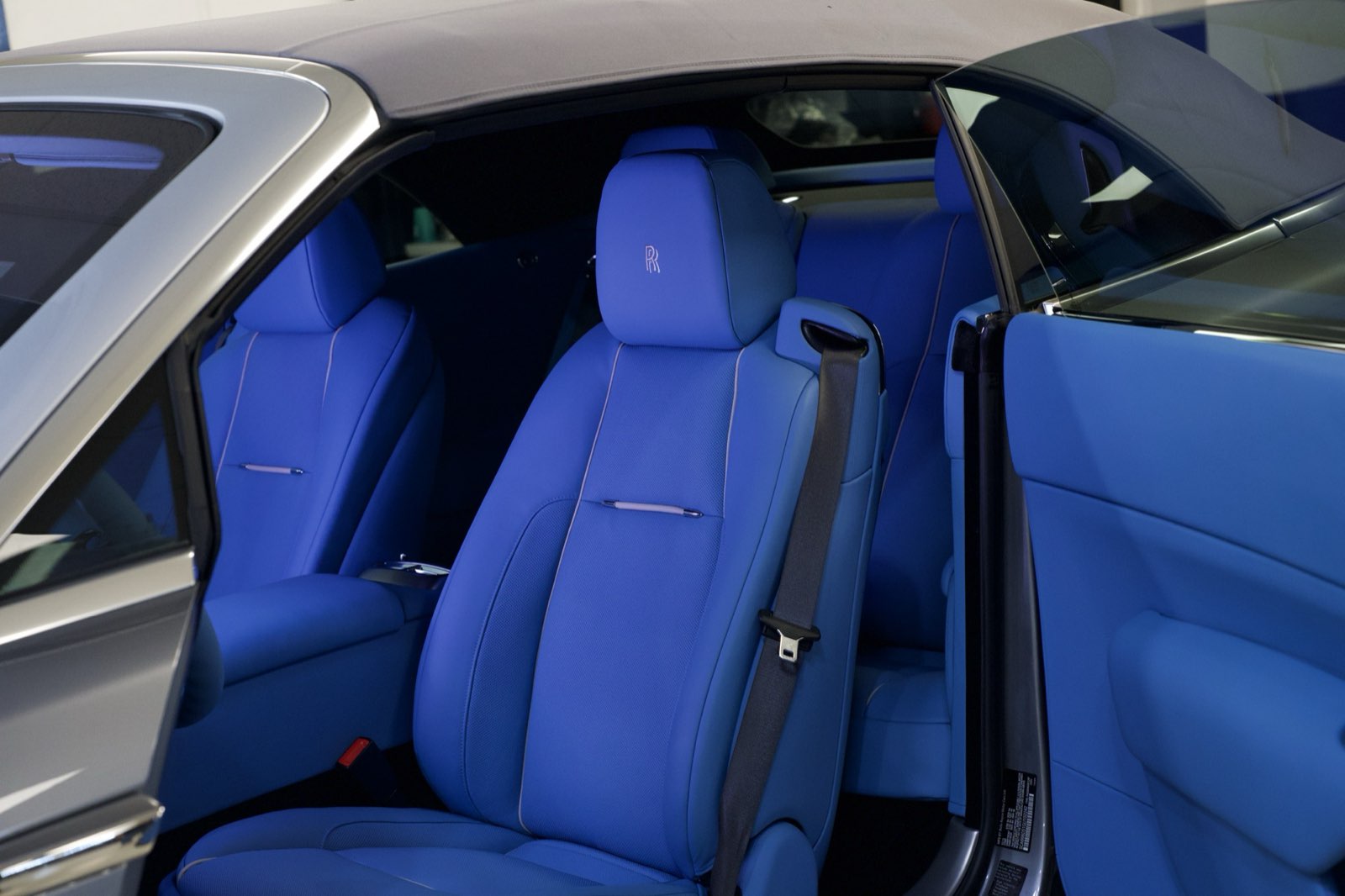 The front seats of a Rolls-Royce in royal blue seen through the door