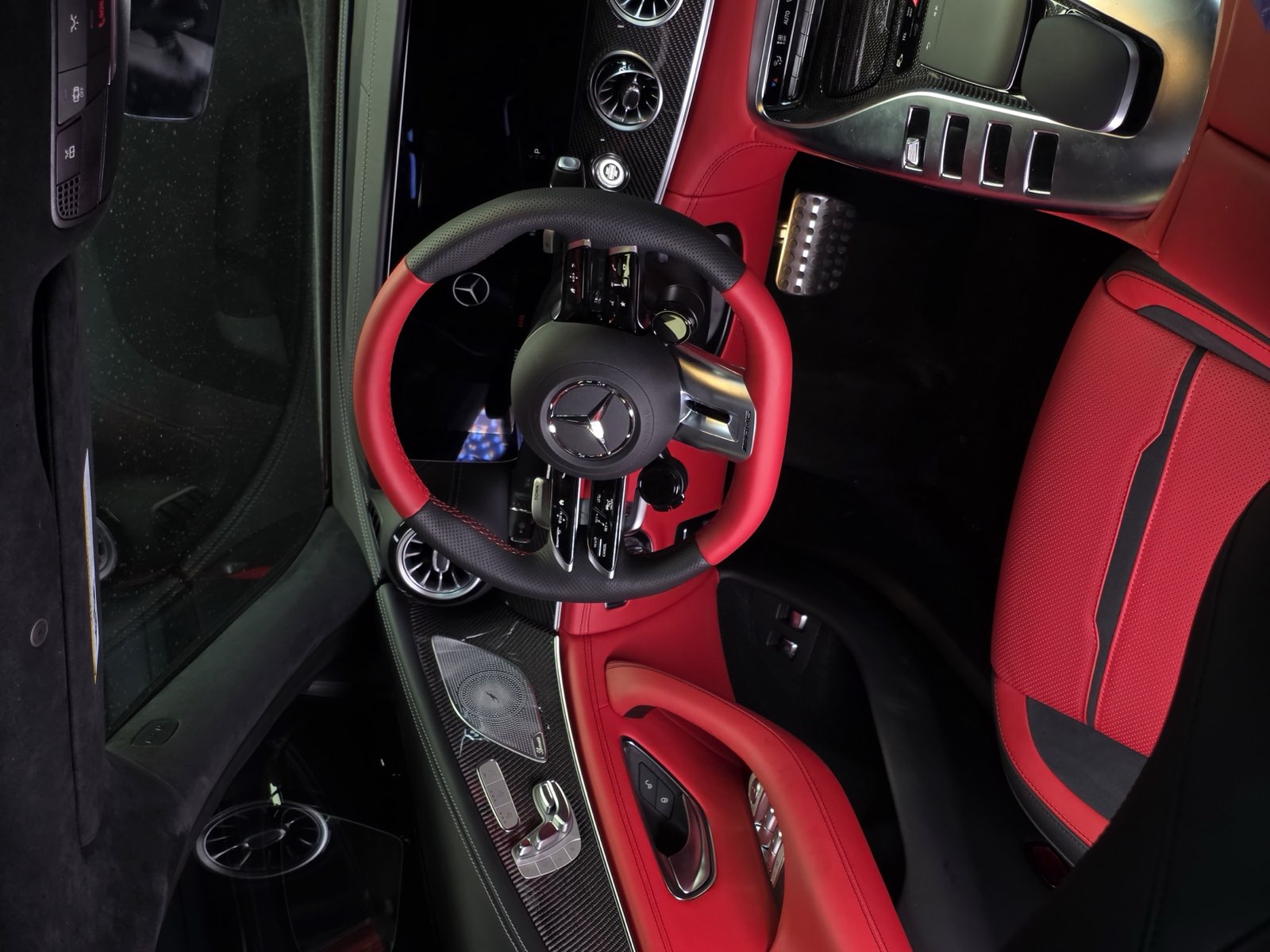 A Mercedes cabin with a red and black steering wheel, red door panels and red seats