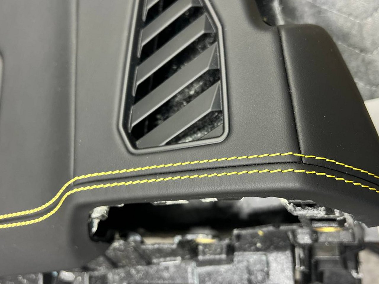 The yellow stitch at the vent: Two rows of yellow thread laid along the edge and around the passenger vent.