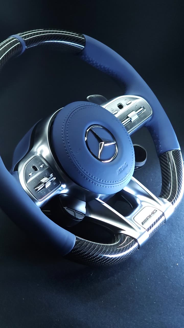 A carbon steering wheel with blue leather grips and a blue leather airbag cover