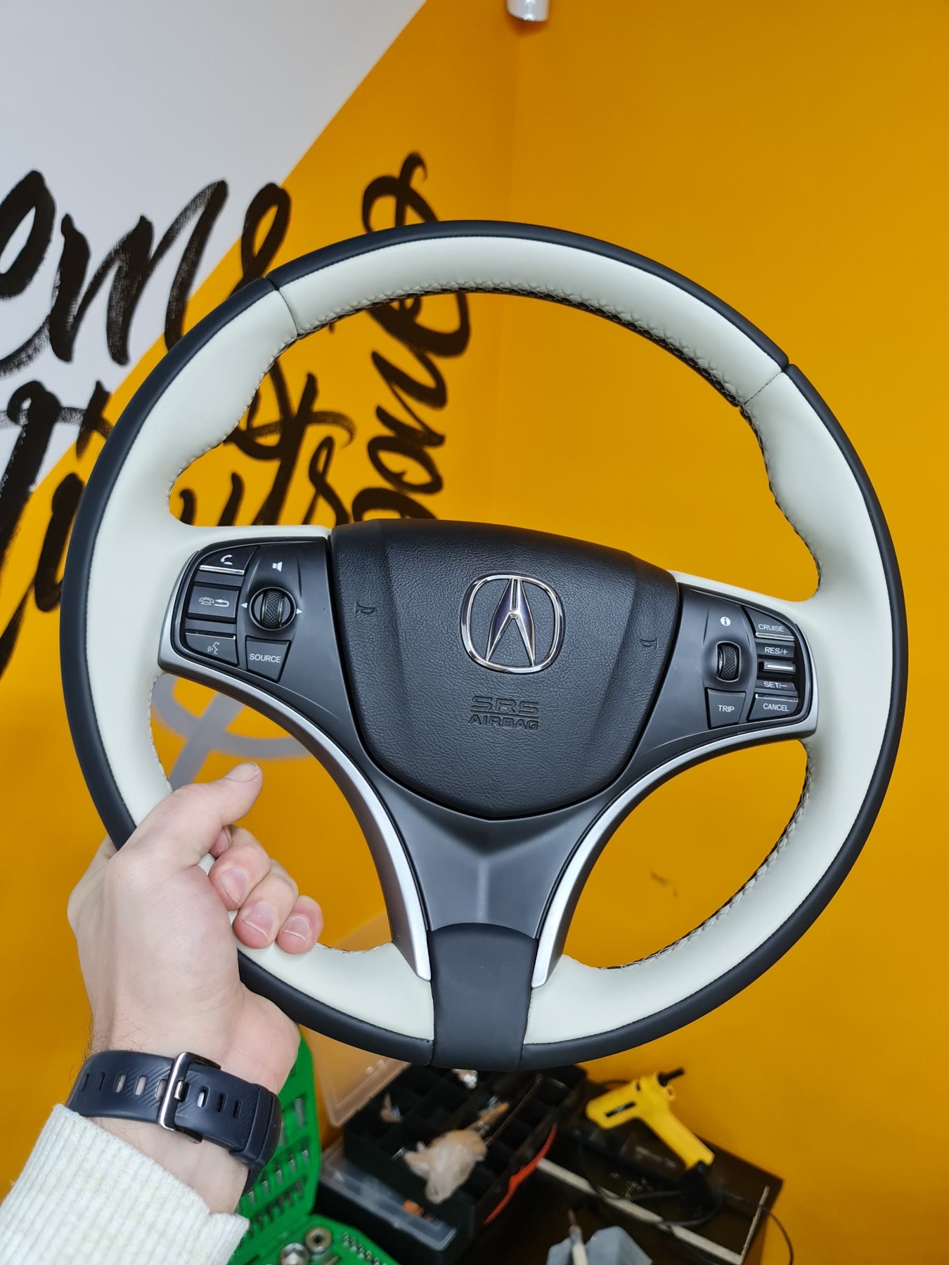 A steering wheel re-trimmed in white leather with black grips