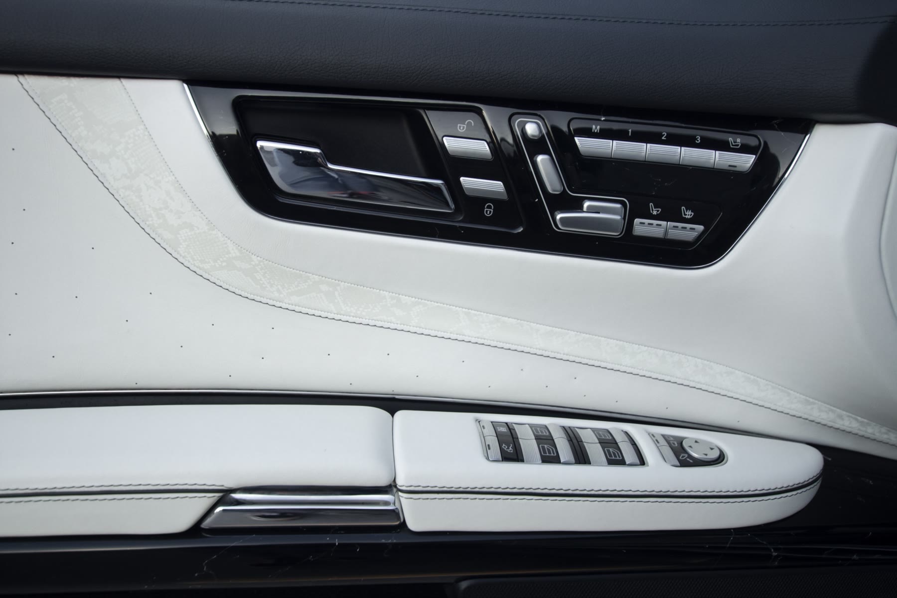 A front door panel in white leather with the seat switches