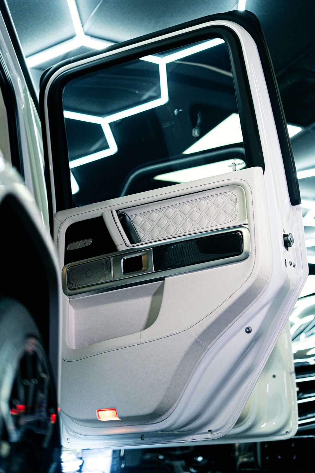 An open G-Wagon door with a quilted white leather panel